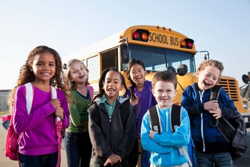 school kids gathering in front of school bus for picture
