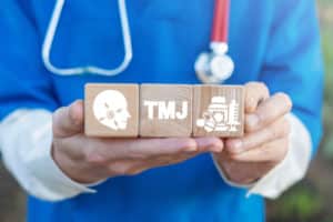 TMJ TMD health care concept on wooden blocks in doctor hands.