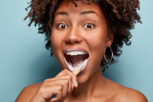 Happy woman smiling while brushing her teeth