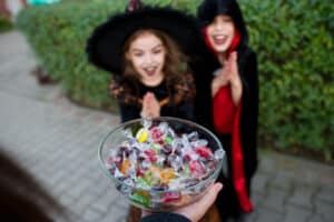 Kids dress in costumes looking at a bowl of Halloween candy