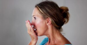 Woman checking how her breath smells against her hand