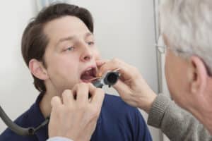 Dentist inspecting man’s tongue to determine potential health issues