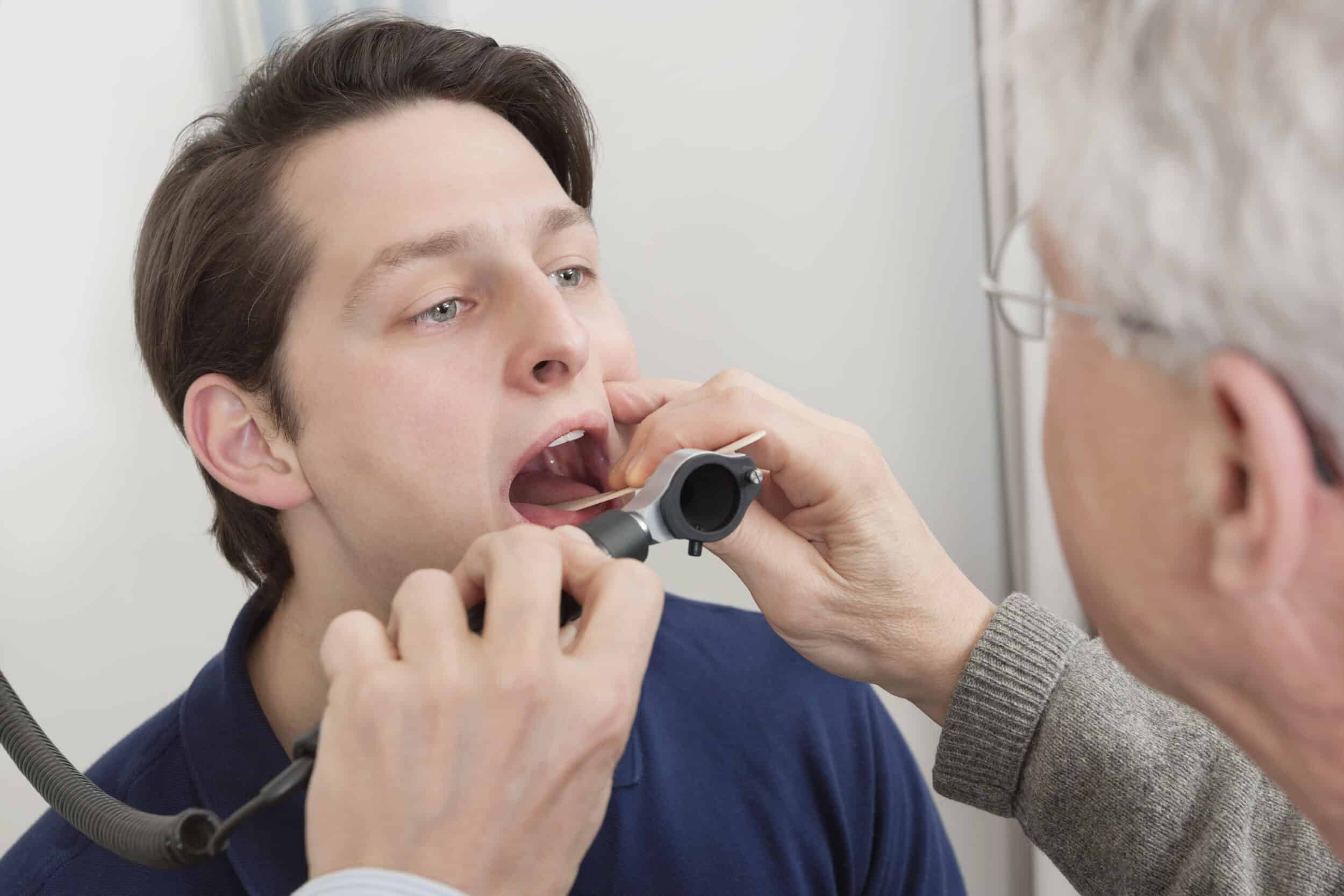 Dentist inspecting man’s tongue to determine potential health issues