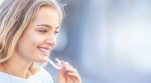 teen girl smiling while putting on her clear aligners